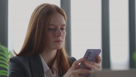 young-businesswoman-is-reading-news-in-mobile-phone-portrait-of-serious-and-depressed-lady-in-office